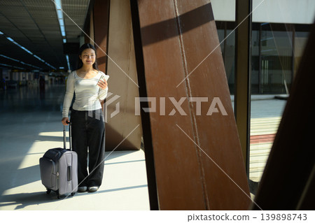 Gen Z traveler using smartphone with suitcase at airport terminal Gen Z traveler using smartphone with suitcase at airport terminal 139898743