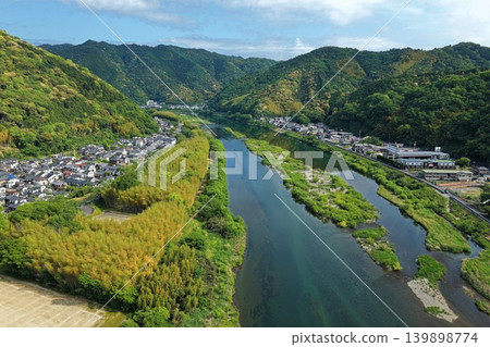 An aerial photograph overlooking a settlement along the Nishiki River and the surrounding green mountains in Iwakuni City, Yamaguchi Prefecture. 139898774