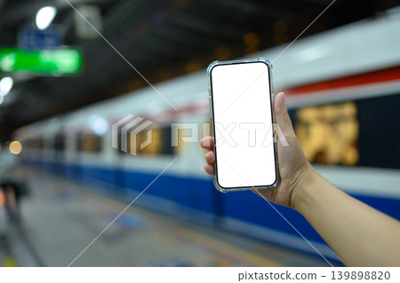 Hand holding smartphone at empty with clipping path in train station platform 139898820