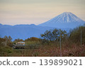 At dusk, a local train travels through a idyllic landscape with Mount Fuji in the background. 139899021