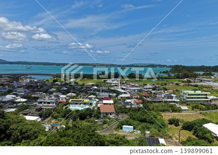 空拍照片顯示了沖繩縣名護市的沿海居民點和碧綠的海。 空拍照片顯示了沖繩縣名護市的沿海居民點和碧綠的海。 139899061