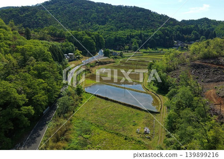 An aerial photograph overlooking rice paddies and mountain paths in a rural area. An aerial photograph overlooking rice paddies and mountain paths in a rural area. 139899216
