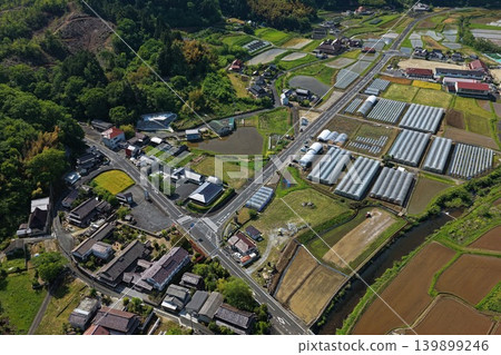一張春季航拍照片,展現了日本鄉村居民點、稻田和溫室的全景。 一張春季航拍照片,展現了日本鄉村居民點、稻田和溫室的全景。 139899246