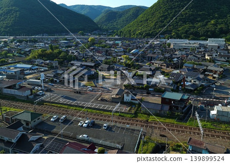 一張空拍照片,展現了岡山縣備前市伊部站周圍的住宅區和山脈。 一張空拍照片,展現了岡山縣備前市伊部站周圍的住宅區和山脈。 139899524