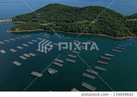 從空中俯瞰瀨戶內市奧町蟲名的牡蠣養殖筏和長島。 從空中俯瞰瀨戶內市奧町蟲名的牡蠣養殖筏和長島。 139899682