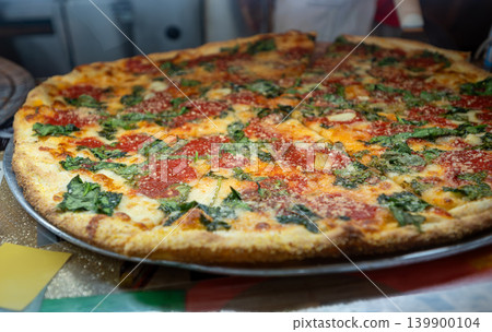 New york, usa august 19,2024. Large thin crust spinach pizza with tomato sauce and melted mozzarella, freshly baked and ready to serve at a pizzeria, close up New york, usa august 19,2024. Large thin crust spinach pizza with tomato sauce and melted mozzarella, freshly baked and ready to serve at a pizzeria, close up 139900104