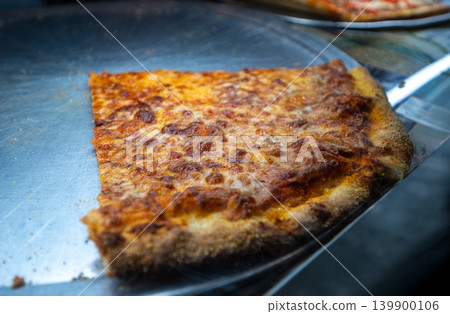 New york, usa august 19,2024. Classic new york city cheese pizza slice on a metal peel, golden melted mozzarella and crispy crust ready for a quick bite New york, usa august 19,2024. Classic new york city cheese pizza slice on a metal peel, golden melted mozzarella and crispy crust ready for a quick bite 139900106