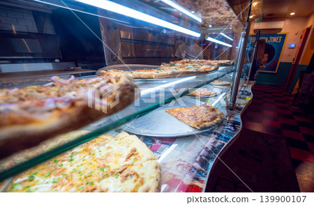New york, usa august 19,2024. Pizza slices with various toppings are visible in a gleaming display case at a new york city pizzeria, ready for customers New york, usa august 19,2024. Pizza slices with various toppings are visible in a gleaming display case at a new york city pizzeria, ready for customers 139900107