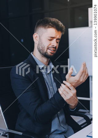 A man with a sore throat works inside the office, a businessman at work has a sore throat flu and cold, uses a laptop at work. 139901074