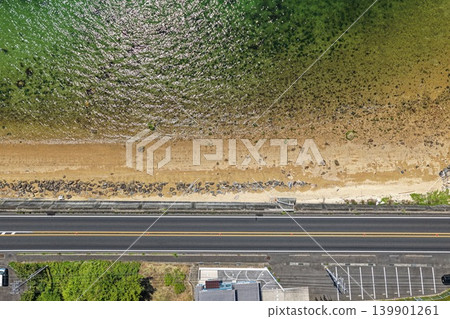 Aerial photograph showing the coastline, beaches, breakwaters, and roads of Hatsukaichi City, Hiroshima Prefecture. 139901261