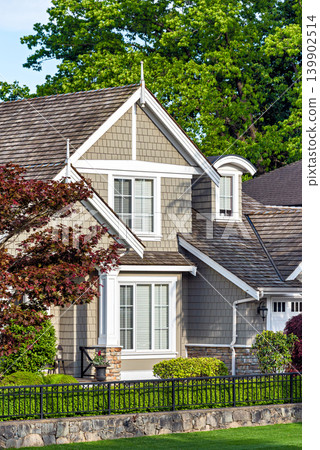 Elegant Residential House. Facade with Sand Tone. White Trim Behind a Black Fence Elegant Residential House. Facade with Sand Tone. White Trim Behind a Black Fence 139902514