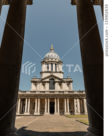 Symmetrically framed by two massive foreground columns, this perspective centers on the magnificent ribbed dome and golden finial of the Chapel of St. Peter and St. Paul at Greenwich's Old Royal Naval Symmetrically framed by two massive foreground columns, this perspective centers on the magnificent ribbed dome and golden finial of the Chapel of St. Peter and St. Paul at Greenwich's Old Royal Naval 139902639