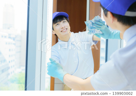 一位年輕的男清潔工正在辦公大樓的洗手間裡擦拭鏡子。照片由東京電子電波學園提供。 139903002