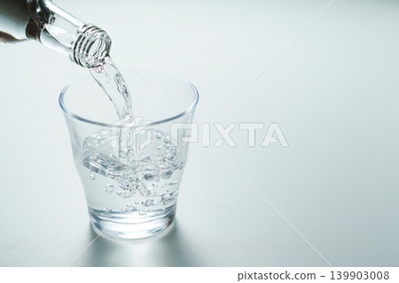 將瓶裝礦泉水倒入玻璃杯中。 139903008