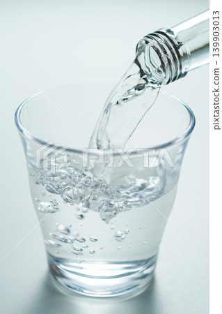 Pour bottled mineral water into a glass. Pour bottled mineral water into a glass. 139903013