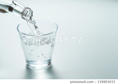 Pour bottled mineral water into a glass. Pour bottled mineral water into a glass. 139903015