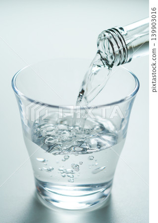 Pour bottled mineral water into a glass. Pour bottled mineral water into a glass. 139903016