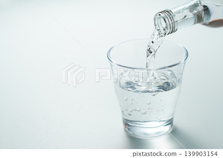 將瓶裝礦泉水倒入玻璃杯中。 139903154