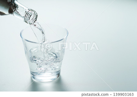 將瓶裝礦泉水倒入玻璃杯中。 139903163