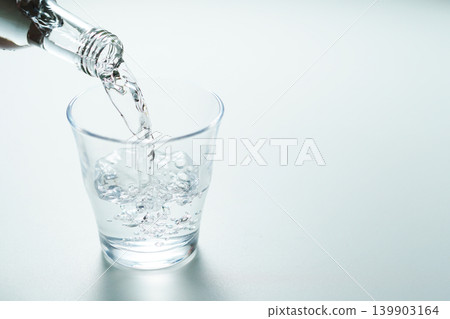 Pour bottled mineral water into a glass. Pour bottled mineral water into a glass. 139903164