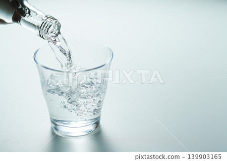 Pour bottled mineral water into a glass. Pour bottled mineral water into a glass. 139903165