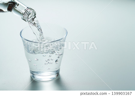 Pour bottled mineral water into a glass. Pour bottled mineral water into a glass. 139903167