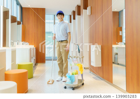 A young Japanese male cleaner stands in a restroom in an office building. Photo courtesy of Denpa Gakuen Tokyo Electronics College. 139903283