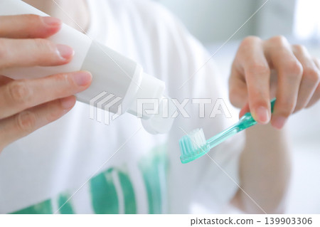 一位女士正在往牙刷上擠牙膏。 139903306
