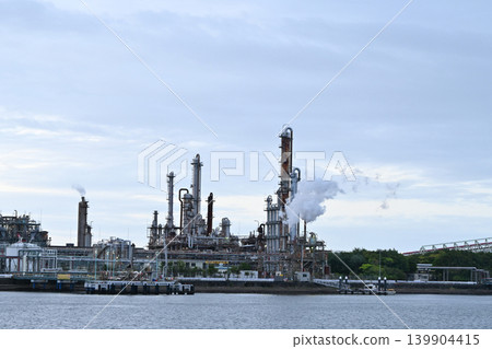 Industrial scenery of a factory plant seen across the water. Industrial scenery of a factory plant seen across the water. 139904415