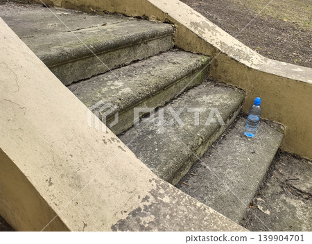 Plastic Water Bottle on Old Weathered Concrete Stairs Plastic Water Bottle on Old Weathered Concrete Stairs 139904701