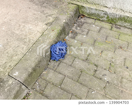 Coil of Blue Rope on Paving Stones Coil of Blue Rope on Paving Stones 139904703