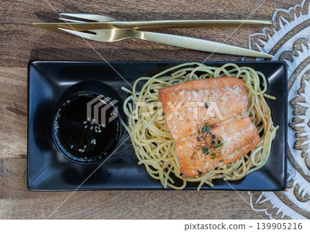 Gourmet Grilled Salmon & Spaghetti Set, A beautifully presented fusion dish showcasing a tender, herb-crusted grilled salmon fillet served over a bed of fine spaghetti. Paired with a signature dark Gourmet Grilled Salmon & Spaghetti Set, A beautifully presented fusion dish showcasing a tender, herb-crusted grilled salmon fillet served over a bed of fine spaghetti. Paired with a signature dark 139905216