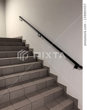 Public Staircase with Grey Floor Tiles and Black Metal Handrail Public Staircase with Grey Floor Tiles and Black Metal Handrail 139905457