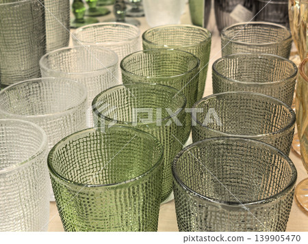 Textured green and clear glass tumblers arranged on wooden table closeup Textured green and clear glass tumblers arranged on wooden table closeup 139905470