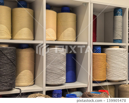 Large industrial yarn cones on shelves in carpet manufacturing factory Large industrial yarn cones on shelves in carpet manufacturing factory 139905478