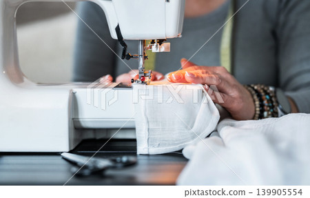 Sewing a Garment on a White Machine in a Workspace Sewing a Garment on a White Machine in a Workspace 139905554