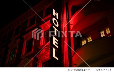 Vertical Hotel Sign Shines on Red Lit Building at Night Vertical Hotel Sign Shines on Red Lit Building at Night 139905573