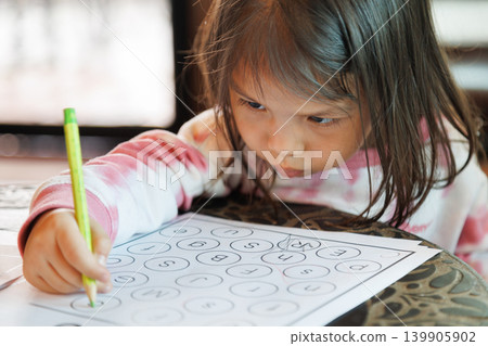 portrait of cute little Asian girl holding a pencil and writing on paper worksheet. focused preschool child doing homework at home or school for early childhood education and development concept. portrait of cute little Asian girl holding a pencil and writing on paper worksheet. focused preschool child doing homework at home or school for early childhood education and development concept. 139905902