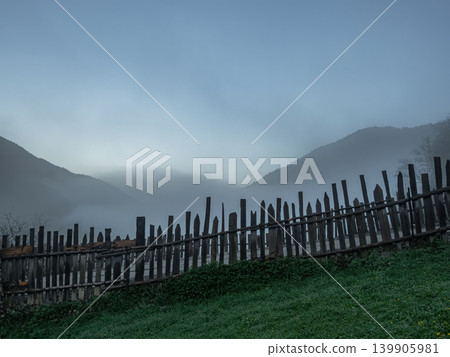 wooden fence in the foreground, thick fog shrouding the mountain peaks wooden fence in the foreground, thick fog shrouding the mountain peaks 139905981