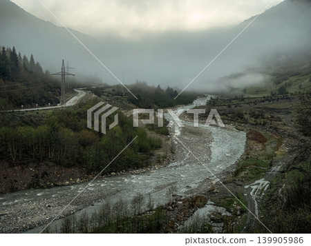 Misty mountain stream winds through green valleys Misty mountain stream winds through green valleys 139905986