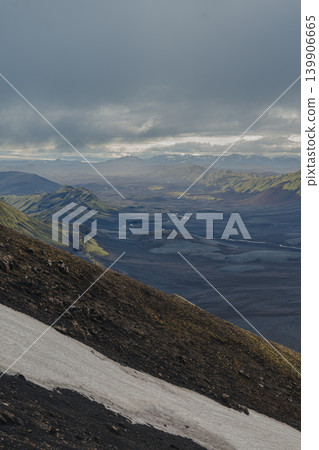 Overcast View of Volcanic Terrain, Snow, and Green Hills in Iceland Overcast View of Volcanic Terrain, Snow, and Green Hills in Iceland 139906665