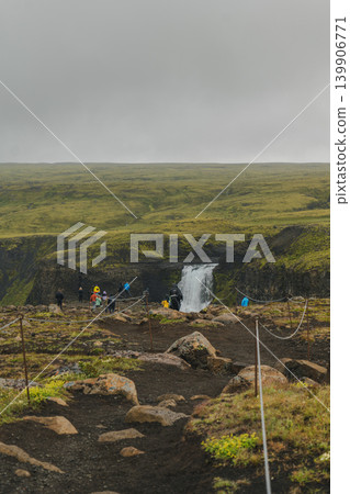 Waterfall Cascading into Canyon with Visitors on Dirt Path in Iceland Waterfall Cascading into Canyon with Visitors on Dirt Path in Iceland 139906771
