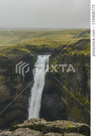 Tall Waterfall Cascading into a Canyon in Iceland's Rugged Terrain Tall Waterfall Cascading into a Canyon in Iceland's Rugged Terrain 139906775