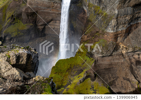 Waterfall Cascading Down Cliff with Rainbow in Iceland 139906945
