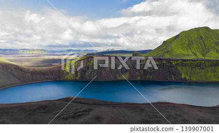 Volcanic Crater Lake and Grassy Mountain in Iceland's Rugged Terrain Volcanic Crater Lake and Grassy Mountain in Iceland's Rugged Terrain 139907001