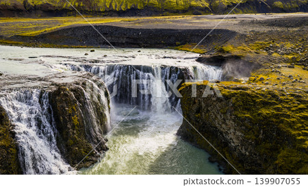 Aerial View of Icelandic Waterfall with Volcanic Terrain and Green Cliffs 139907055