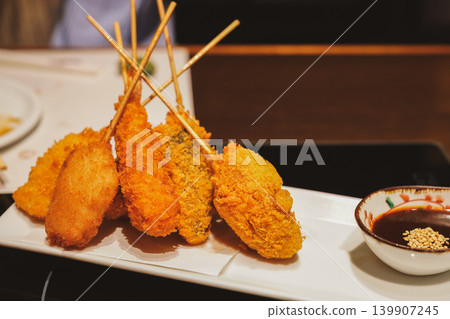 A set of delicious-looking deep-fried skewers with a crispy batter and sauce. A set of delicious-looking deep-fried skewers with a crispy batter and sauce. 139907245