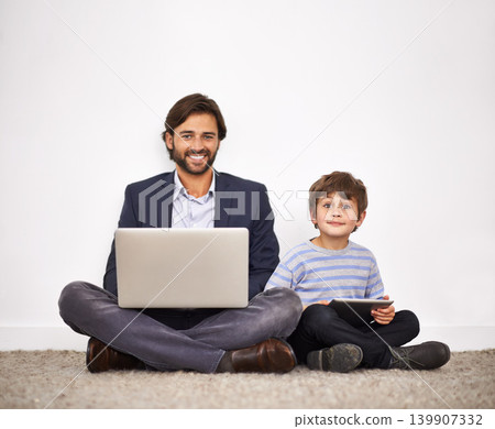 Father, happy kid and portrait with laptop, tablet and learning with boy at home by wall. Smile, child and dad on computer with tech for remote work, love or connection of family together on floor Father, happy kid and portrait with laptop, tablet and learning with boy at home by wall. Smile, child and dad on computer with tech for remote work, love or connection of family together on floor 139907332
