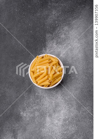 Italian uncooked dry penne regate pasta ready for cooking. Dry penne pasta Italian uncooked dry penne regate pasta ready for cooking. Dry penne pasta 139907356