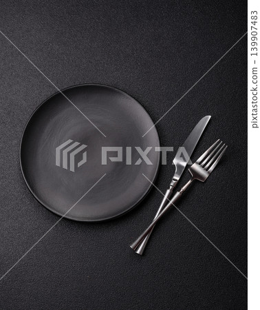An empty ceramic round plate, kitchen utensils for a dinner table. An empty plate An empty ceramic round plate, kitchen utensils for a dinner table. An empty plate 139907483